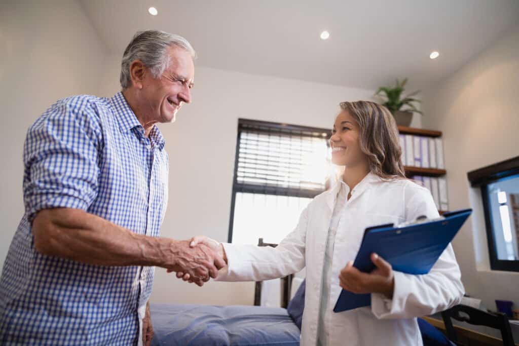 Smiling senior male patient and female therapist shaking hands